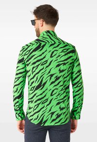 Žalia marškiniai su juodu tigro juostų raštu, ilgomis rankovėmis, apykakle ir mygtukais rankogaliuose, pagaminti iš lengvos medžiagos.