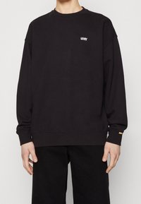 Felpa nera con collo rotondo, vestibilità rilassata, con un piccolo logo bianco Levi's sul petto e un accento arancione sulla manica.