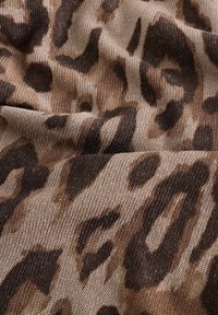 Leopardenmusterstoff mit weichem, strukturiertem Strick in Beige-, Braun- und Schwarztönen und unregelmäßigen Mustern.