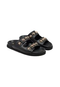 Sandali in pelle nera con due cinture larghe, decorati con borchie dorate metalliche. Sole piatto e design open-toe per una facile indossabilità.