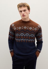 Gestrickter Pullover mit einem geometrischen Muster in Braun, Marineblau und Grau. Hoher Kragen, lange Ärmel sowie gerippte Bündchen und Saum.