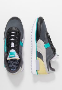 Scarpe sportive con punta in pelle nera, tomaia in tessuto grigio, dettagli turchesi e suola bianca texturizzata con particolari gialli.