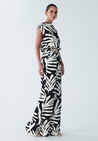 Melna un balta kleita ar lapu rakstiem, bez piedurknēm, ar savilkumu viduklī, grīdas garuma, izgatavota no viegla auduma. Stilizēta ar zelta akcentiem.