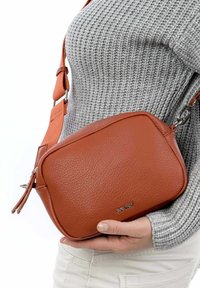 Brown leather crossbody bag with a textured finish, rectangular shape, adjustable orange strap, and silver hardware accents.