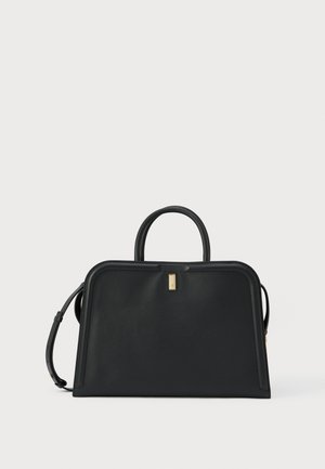 Czarna, strukturyzowana torebka z uchwytami od góry, złotym, prostokątnym zapięciem oraz regulowanym paskiem na ramię na jednolitym białym tle.