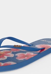 Μπλε σανδάλι flip-flop με σχέδιο από ροζ και λευκά λουλούδια στη σόλα και μπλε λουριά με μικρό λογότυπο "Roxy".