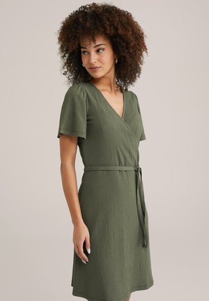 Rochie elegantă cu textură verde, de tip wrap, cu decolteu în V, mâneci scurte și cordon la talie. Siluetă fluidă cu un finisaj dintr-o țesătură moale.