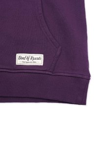 Lila ekologisk bomullshoodie med känguruficka, ribbat nederfoder och en vävd etikett med "Band of Rascals" och produktinformation.