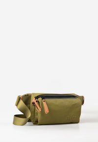 Olive green waist bag with black zipper, two tan leather zipper pulls, and adjustable olive strap laid on white surface.