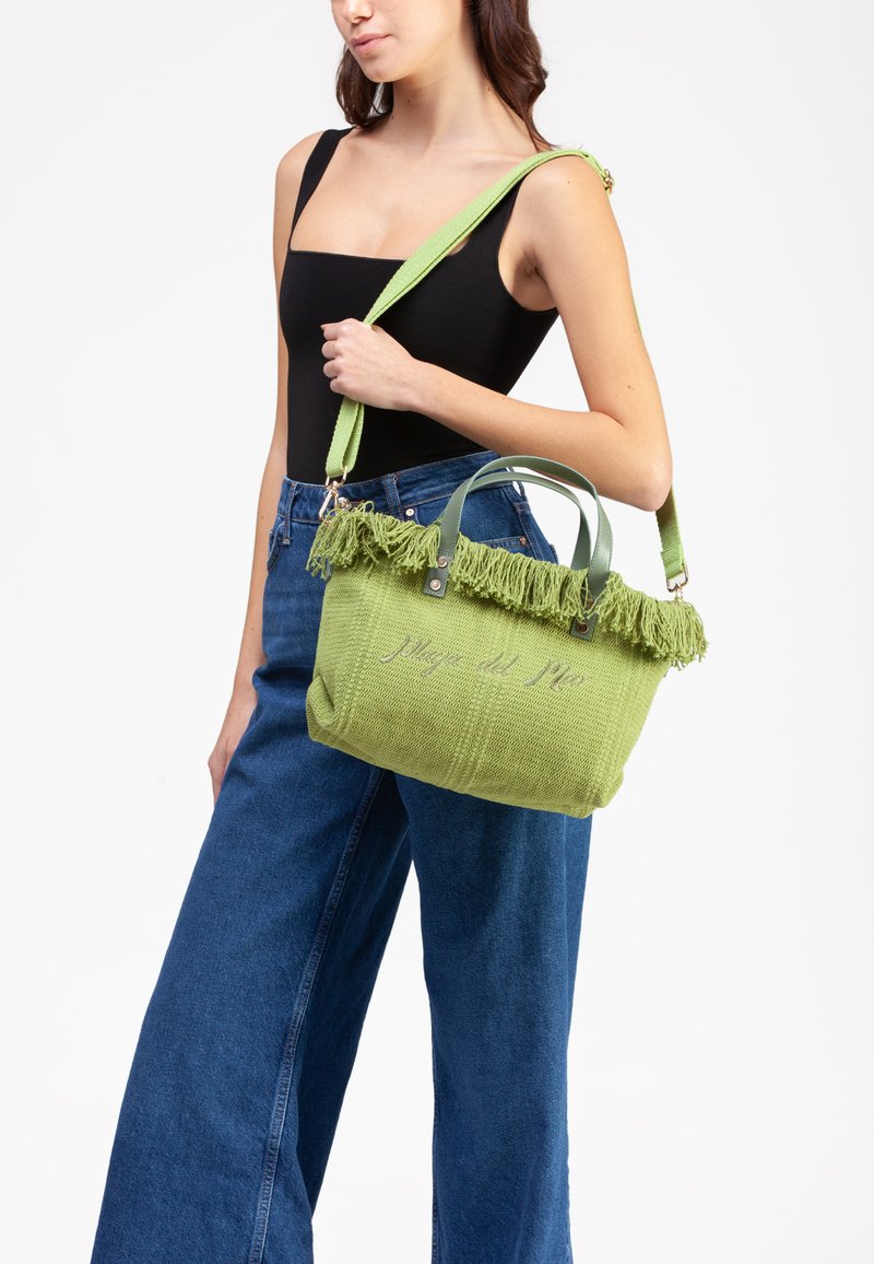 Borsa a tracolla verde in maglia con bordo superiore frangiato, doppi manici e tracolla rimovibile. Presenta il testo ricamato "Plage del Rio."