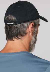 Czapka wojskowa w wzór kamuflażu, z regulowanym paskiem. Na tyle napisana jest nazwa "CAMP DAVID", wykonana z teksturowanej bawełny. Widoczne przeszycia.