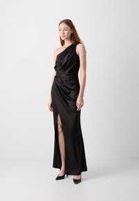 Melnas satīna kleitas ar vienu plecu, ar sānu šķēlumu un drapēta dizaina, iekļaujot slaidas līnijas un pieguļošu vidukli. Modelis valkā melnas papēžu kurpes.