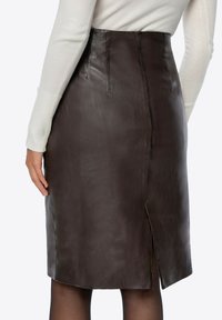 Brązowa skórzana ołówkowa spódnica z tylnym rozcięciem, gładka w dotyku, dopasowany fason oraz ozdobne przeszycia wzdłuż talii i szwów.