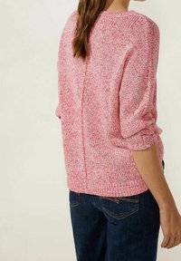 Texturerad stickad tröja i blandade rosa nyanser, med en avslappnad passform, rullade ärmslut och en sömdetalj bak. Matchas med mörka denimjeans.