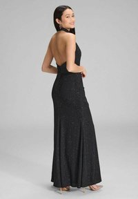 Schwarzes Halterneck-Kleid mit offenem Rücken, aus strukturiertem Glitzerstoff; taillierte Silhouette mit einem bodenlangen Rock und seitlichem Schlitz.