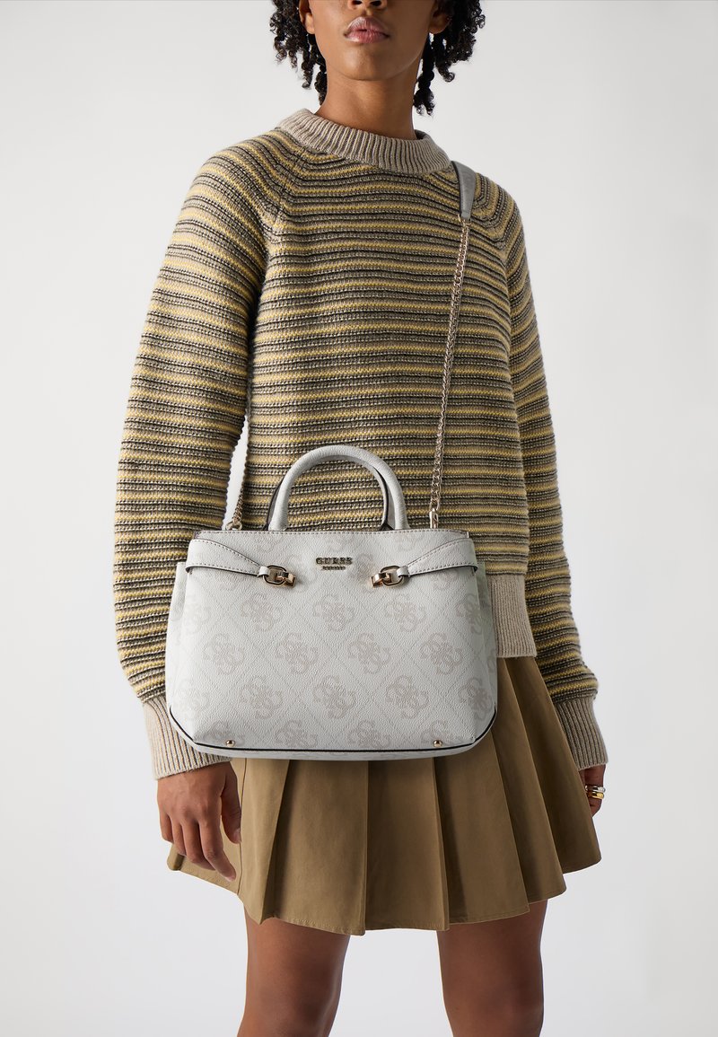 Borsa strutturata grigia chiara con doppi manici, hardware argentato, motivo con logo e tracolla a catena staccabile, abbinata a un maglione a righe e a una gonna.