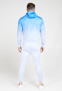 Felpa blu chiaro con design ombré, dotata di colletto alto e maniche lunghe, abbinata a pantaloni jogger fitted blu chiaro.