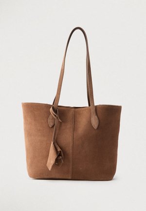 Sac cabas en daim marron avec doubles bretelles et petite pochette suspendue sur fond clair.