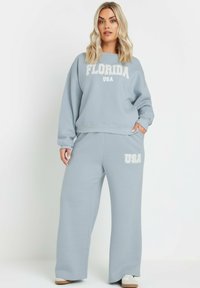 Conjunto de sudadera y pantalones de chándal de color azul claro, con "FLORIDA" y "USA" en texto blanco, de corte relajado y textura suave.