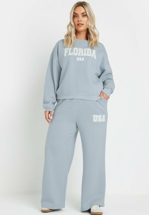 Ensemble de sweatshirt et pantalon de jogging bleu clair, arborant "FLORIDE" et "ÉTATS-UNIS" en texte blanc, avec une coupe décontractée et une texture douce.
