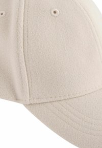 Beige uld baseball cap med en buet skygge, sømløst design, struktureret overflade og to ventilationshuller på kronen.