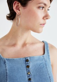 Denim top met een vierkante halslijn, voorzien van drie decoratieve knopen: twee rozenontwerpen en één hart, in een lichtblauwe kleur.