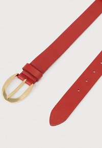 Κόκκινη δερμάτινη ζώνη με υφή, με αγκράφα από μεταλλικό υλικό σε χρυσό τόνο και διάτρητες τρύπες για ρύθμιση. Λείο, επίπεδο σχέδιο λουριού.