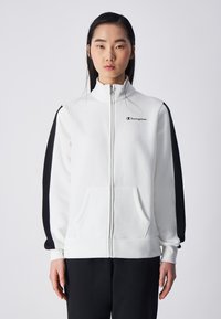Witte zip-up sweatshirt met zwarte zijstrepen, Champion-logo op de borst, hoge kraag, twee voorzakken en ribgebreide manchetten. Zachte stoftextuur.