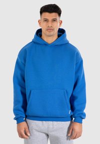 Blauwe capuchon sweatshirt gemaakt van zacht materiaal, met een voorzak en geribbelde boorden. Het ontwerp heeft een ontspannen pasvorm en een levendige kleur.