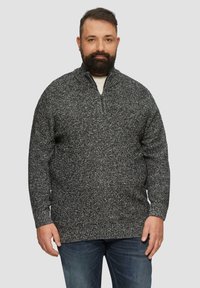 Dunkelgrauer und weiß gesprenkelter Strickpullover mit einem Reißverschlusskragen, langen Ärmeln und gerippten Bündchen, präsentiert an einem männlichen Modell vor einem hellen Hintergrund.