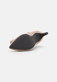 Zapato de ante de punta en rosa empolvado con una suela de goma negra. El tacón es bajo, con una textura suave y un diseño minimalista.