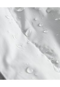 Tessuto impermeabile di un grigio chiaro con gocce d'acqua visibili. Texture liscia con una leggera lucentezza; le cuciture sono ben rifinite.