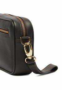 Tumma ruskea nahkainen laukku, jossa on teksturoitu pinta, kultaiset vetoketjut ja solki, suorakulmainen muoto ja säädettävä hihna.