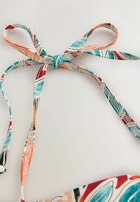 Daudzkrāsainas auduma lentes ar ziedu rakstu, sazīmētas lokā. Lentēm ir tirkīza, koraļļu, melnas un krēmkrāsas toņi.