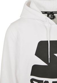 Bílá mikina s kapucí a velkým černým logem. Obsahuje stahovací kapuci a měkkou, hladkou texturu. Štítek uvádí "Starter Black Label."