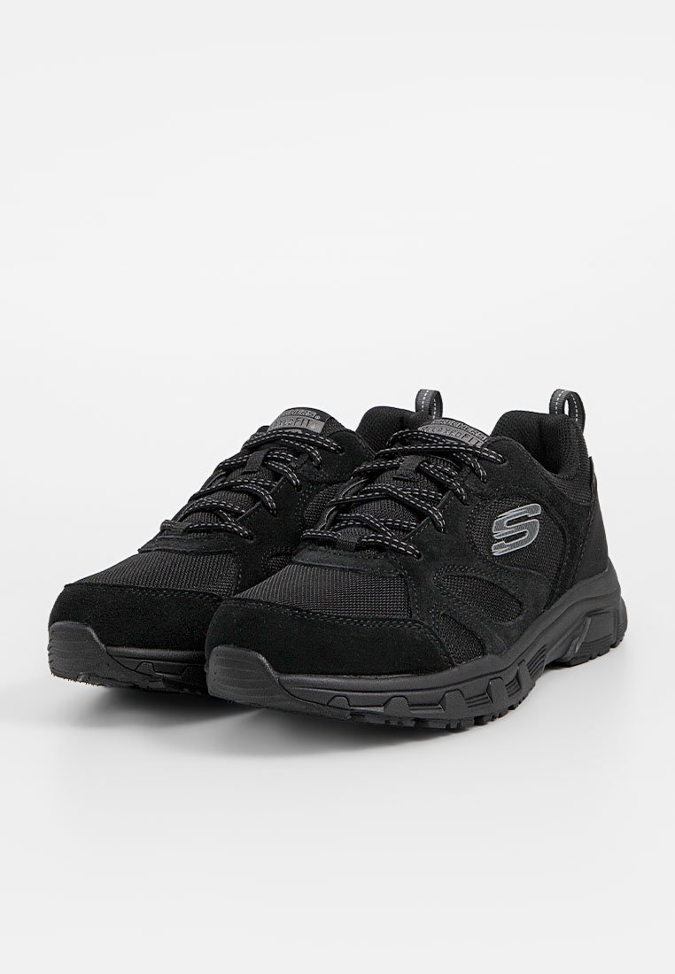 Zwarte sportieve schoenen van mesh en suède materialen, met een gestructureerd oppervlak, ronde neus, dikke rubberen zolen en vetersluiting met een logo.