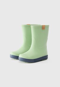 Botas de lluvia de goma verdes con suelas azul marino, que presentan una textura lisa y una etiqueta marrón claro en la parte superior del caña para la marca.