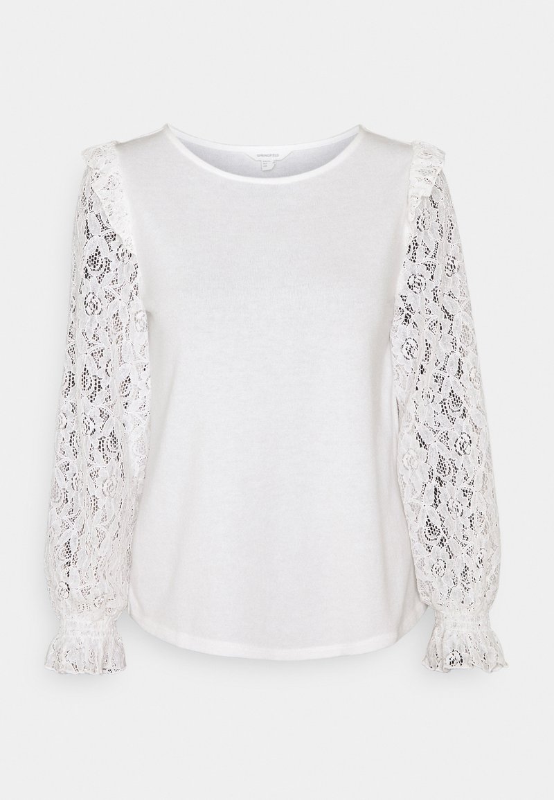 Haut blanc à manches longues avec col rond et manches transparentes en dentelle florale, doté de poignets à volants et de légers détails froncés aux épaules.