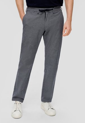 Pantalones de cuadros grises con un corte relajado, que cuentan con una cinturilla tradicional, bolsillos delanteros y tela transpirable. Combinados con zapatillas blancas.