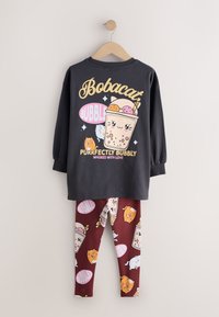 Haut noir à manches longues avec un graphique bubble tea souriant et des chats, associé à des leggings bordeaux avec des imprimés assortis de bubble tea et de chats.