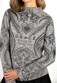 Gray sweater made of soft fabric featuring intricate black paisley patterns and the text "GRACE STUDIO COLLECTION" prominently displayed.