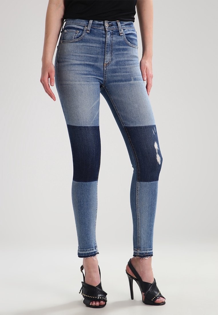 Jeans ajustados en varios tonos de denim azul, con un diseño de patchwork en dos tonos y detalles desgastados cerca de la rodilla.