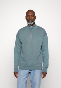 VADEDE blauwe zip-up sweater met een hoge kraag en geribde manchetten, gemaakt van een zachte stof. Het heeft een minimalistisch ontwerp en een casual pasvorm.