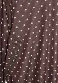 Tessuto trasparente marrone con pois bianchi. La texture sembra leggera e leggermente traslucida, con un effetto di caduta sottile.