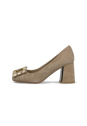 Zapato de tacón bloque de ante beige con punta cuadrada y una gran hebilla decorativa de oro y cristal en la parte delantera.