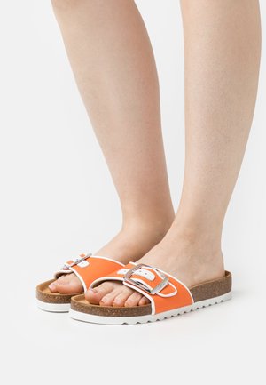 Chanclas naranjas con una gruesa suela de corcho, acentos en blanco y un detalle de hebilla plateada. El diseño presenta una punta abierta y un estilo de plantilla.