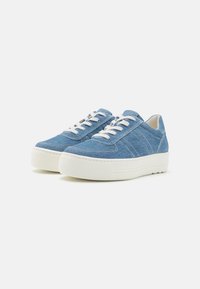 Baskets en denim bleu avec semelle en caoutchouc blanc, dotées de lacets plats blancs et d'accents cousus sur les côtés. Bout arrondi et design bas.