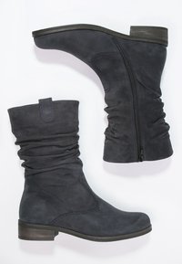 Par de botas de ante gris oscuro hasta la mitad de la pantorrilla con caña caída, cremallera lateral, tacón bajo apilado y punta redonda, exhibidas sobre fondo blanco.
