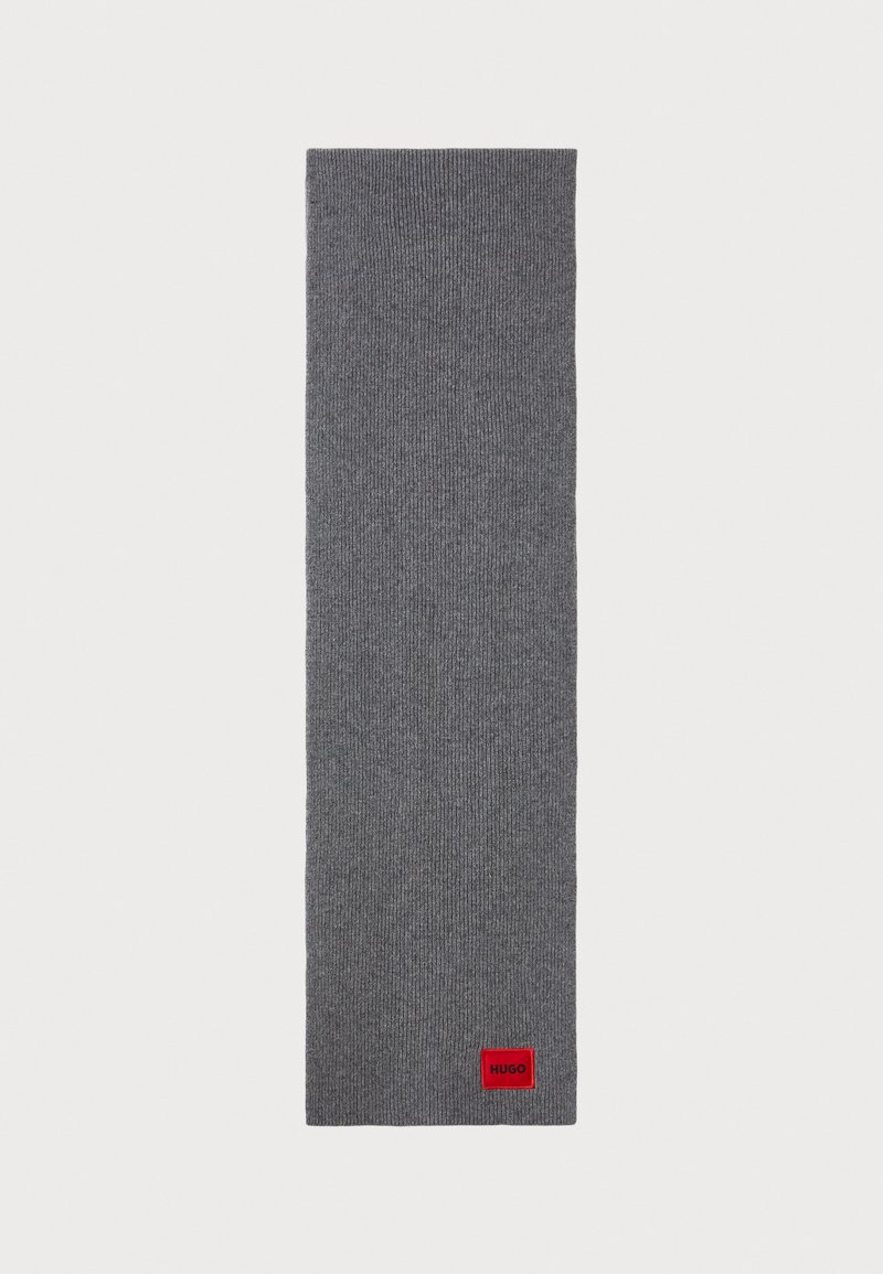 Gray knitted scarf with ribbed texture. Features a small red branded tag at one end. Long, rectangular shape ideal for wrapping.