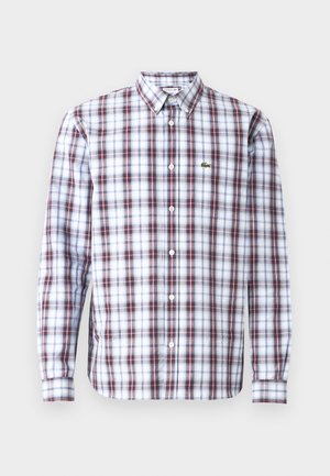 Hosszú ujjú gombos ing, piros, kék és fehér kockás mintával, könnyű anyagból készült, a mellkason egy kis zöld logóval.